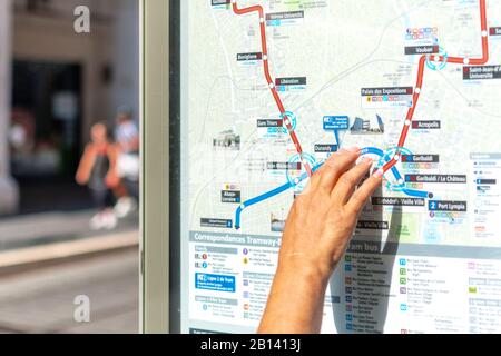 Una mano femminile punta ad una mappa stradale che mostra le linee del tram nel centro di Nizza, in Francia. Foto Stock