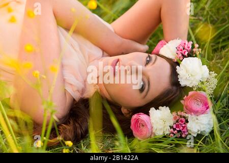 Donna con corona di fiori si trova in un prato Foto Stock