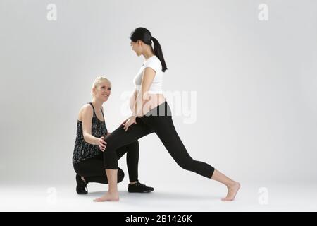 Donna incinta fare esercizi di fitness con un personal trainer Foto Stock