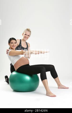 Donna incinta fare esercizi di fitness con un personal trainer Foto Stock