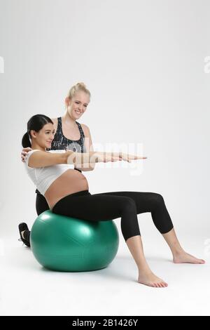 Donna incinta fare esercizi di fitness con un personal trainer Foto Stock