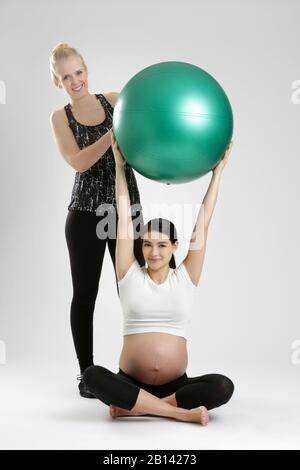 Donna incinta fare esercizi di fitness con un personal trainer Foto Stock