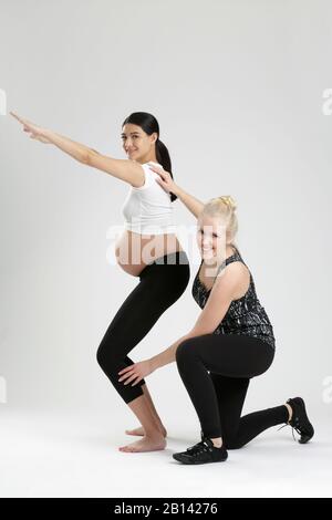 Donna incinta fare esercizi di fitness con un personal trainer Foto Stock