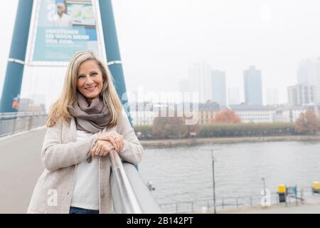 La donna di mezza età sta in piedi su un ponte Foto Stock