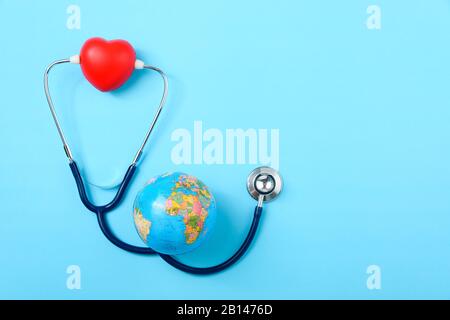 World Health Day Concept, Stethoscope, globo e cuore rosso su sfondo blu con spazio copia. Assistenza sanitaria globale Foto Stock