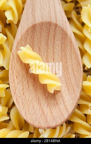 Fusilli Pasta in cucchiaio di legno fondo full frame. Foto Stock