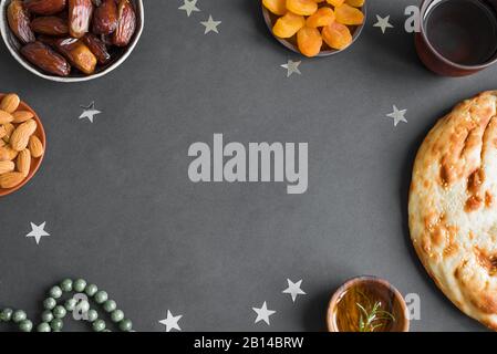 Ramadan iftar cibo - frutta di data, ramadan pane fresco, olio d'oliva, acqua, mandorle, albicocche sul nero, vista dall'alto, copia spazio. Ramadan Kareem concetto. Foto Stock