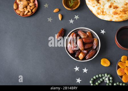 Ramadan iftar cibo - frutta di data, ramadan pane fresco, olio d'oliva, acqua, mandorle, albicocche sul nero, vista dall'alto, copia spazio. Ramadan Kareem concetto. Foto Stock