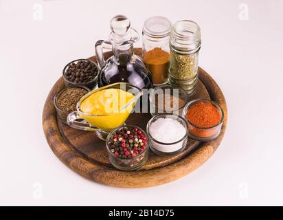 Salse e spezie varie su una tavola di legno su un tavolo bianco. Foto Stock