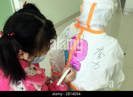 (200223) -- WUHAN, 23 febbraio 2020 (Xinhua) -- UNA bambina colora un dipinto sulla tuta protettiva di un personale medico presso il reparto di isolamento dei bambini infettati da una nuova polmonite da coronavirus nel Wuhan Children's Hospital di Wuhan, nella provincia centrale cinese di Hubei, il 20 febbraio 2020. Al reparto di isolamento dei bambini infettati con la nuova polmonite da coronavirus nel Wuhan Children's Hospital, molti bambini avevano paura di vedere il personale medico avvolto in tute protettive. Wang Jia, infermiera dell'ospedale che ama disegnare, ha fornito l'idea di disegnare cartoni animati sulle tute protettive e sugli invi Foto Stock