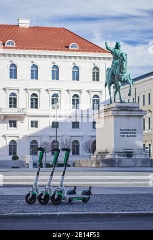 Monaco di Baviera, Germania - 22 febbraio 2020: E-scooters dalla società Lime parcheggiata di fronte alla sede centrale Siemens a Wittelsbacherplatz e la statua di Foto Stock