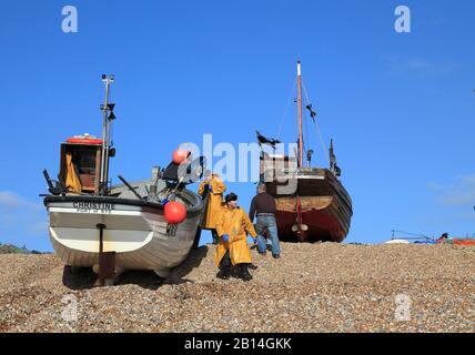 Pescatori di Hastings in yellow oilskins che sbarcano la barca da pesca sulla spiaggia dei pescatori di Old Town Stade, Rock-a-Nore, East Sussex, Regno Unito Foto Stock