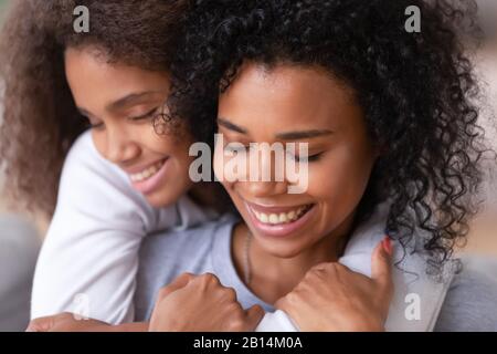 Famiglia di cura single mom e figlia africana teen che abbracciano coccole Foto Stock