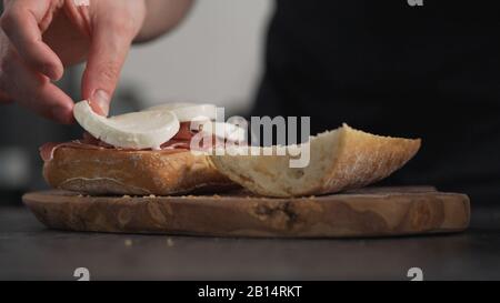 l'uomo aggiunge mozzarella sulla ciabatta a bordo di olive, foto ampia Foto Stock
