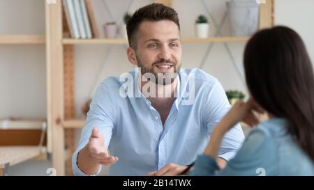 Giovane uomo coinvolto nella conversazione con un collega in carica Foto Stock