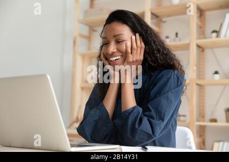 Giovane donna afroamericana sorridente che guarda lo schermo del laptop. Foto Stock