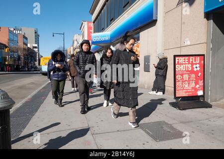 Uomini e donne americani cinesi, tra cui una giovane signora che controlla il suo telefono a piedi su Main Street a Flushing, Queens, New York City. Foto Stock