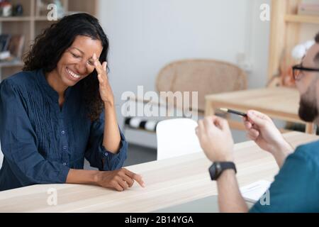 Giovane donna afroamericana che ride, seduto di fronte al reclutatore. Foto Stock