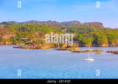 Paesaggio norvegese villaggio scandinavo con fiordo d'acqua, montagne, case tradizionali colorate e barca a vela, Norvegia Foto Stock