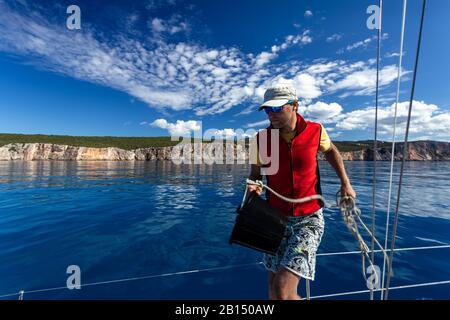 Un uomo con un secchio va al ponte dello yacht, lavaggio. Foto Stock