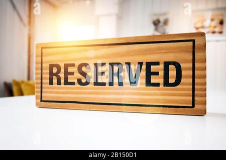 Posti a sedere prenotati al ristorante per incontri nel concetto di Celebrate Day. Ristorante con cartello di legno riservato su tavolo bianco con cafe' decorati Foto Stock