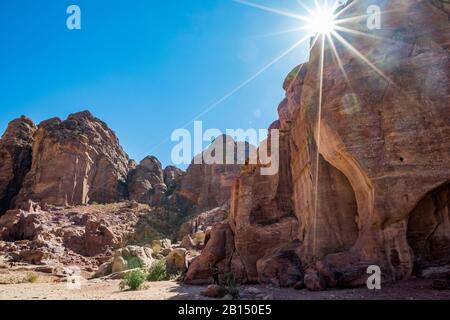 Scogliere e tombe che potrebbero essere viste quando si cammina il paesaggio Street delle Facciate, creato centinaia di anni. Petra complesso attrazione turistica, Regno hascemita di Giordania. Effetto di diffrazione della luce solare Foto Stock