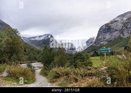 Indicazione del percorso del ghiacciaio di Jostedalsbreen. Vista verde del paesaggio delle montagne. Escursione viaggio Norvegia natura su nuvoloso autunno giorno Foto Stock