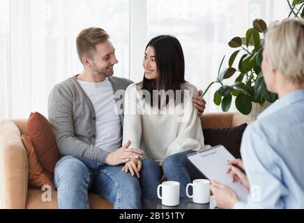 Felice Coppia Abbracciando In Ufficio Di Consigliere Di Famiglia Dopo La Riconciliazione Foto Stock