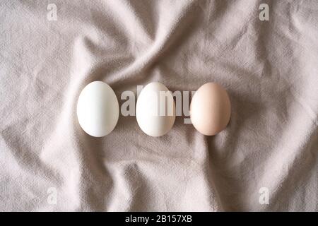 Fila di uova di pollo uguali su fondo di lino naturale. Raccolta di uova di gallina, modello di pasqua. Disposizione piatta, vista dall'alto. Concetto di Pasqua. Foto Stock