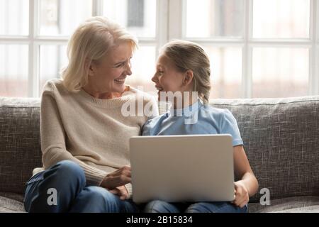 Superjoyed mezza anziana granny e nipote felice della scuola usando il laptop. Foto Stock