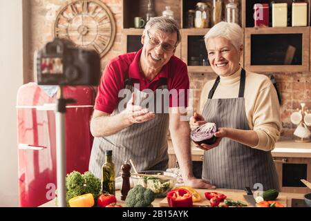 Anziani Coppia Registrazione Video Per Alimentare Blog, Cucina In Cucina Insieme Foto Stock