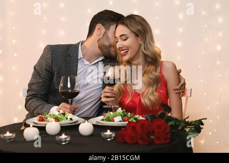 Giovane coppia che ha una serata romantica nel ristorante, abbracciando e bevendo vino Foto Stock