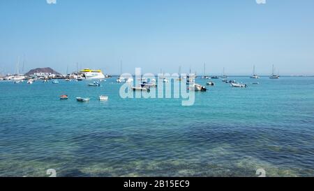 Vista panoramica del porto con molte barche fisse, traghetti e yacht e la lontana isolotto di Los Lobos, Fuerteventura, Spagna Foto Stock