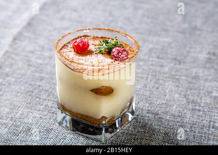 Panna cotta dessert in un vetro trasparente, decorato con ciliegie e menta sulla parte superiore. Foto Stock