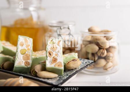 Torrone di organico a base di miele, pistacchi, nocciole, mandorle e i dadi su uno sfondo bianco. Foto Stock