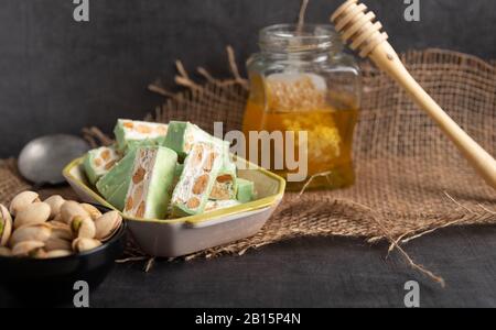 Torrone di organico a base di miele, pistacchi, nocciole, mandorle e i dadi su un rustico sfondo scuro. Foto Stock