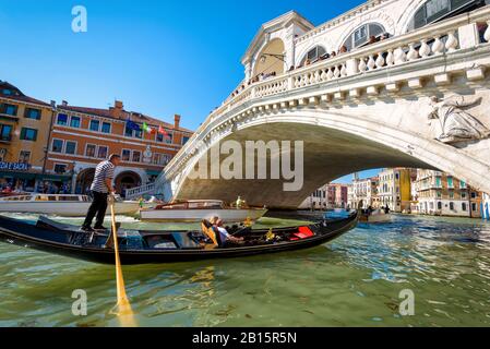 Venezia, Italia - 19 maggio 2017: Gondoliere dirige la gondola con i turisti al Ponte di Rialto sul Canal Grande. La gondola è un tradizionale romante Foto Stock