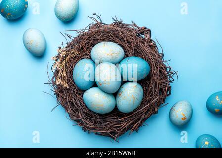 Uova di Pasqua in nido su sfondo blu. Foto Stock