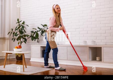 Bella casa moglie pulizia con scopa sua casa. Foto Stock