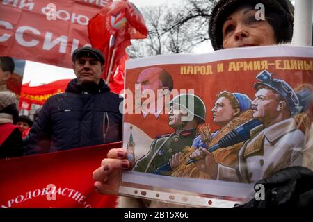 Mosca, Russia. 23rd di febbraio, 2020 Partecipanti ad un rally e ad una marcia nel centro di Mosca che segnano il 102nd anniversario della fondazione dell'Armata Rossa Sovietica e della Marina Sovietica. Una donna tiene un poster con propaganda sovietica dedicato al giorno dell'esercito sovietico con l'iscrizione in russo 'Il Popolo e l'esercito sono Uniti' Foto Stock