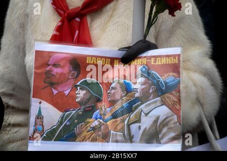 Mosca, Russia. 23rd di febbraio, 2020 Partecipanti ad un rally e ad una marcia nel centro di Mosca che segnano il 102nd anniversario della fondazione dell'Armata Rossa Sovietica e della Marina Sovietica. Una donna tiene un poster con propaganda sovietica dedicato al giorno dell'esercito sovietico con l'iscrizione in russo 'Il Popolo e l'esercito sono Uniti' Foto Stock