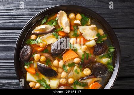 Zuppa sana preparata di fresco con funghi, verdure e ceci in una ciotola sul tavolo. Vista dall'alto orizzontale Foto Stock