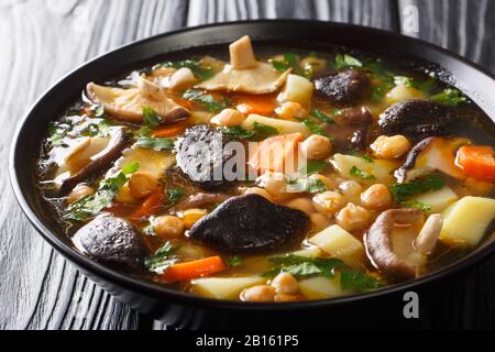 Zuppa sana preparata di fresco con funghi, verdure e ceci in una ciotola sul tavolo. Orizzontale Foto Stock