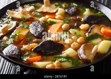 Zuppa di verdure con funghi e ceci da vicino in una ciotola sul tavolo. Orizzontale Foto Stock
