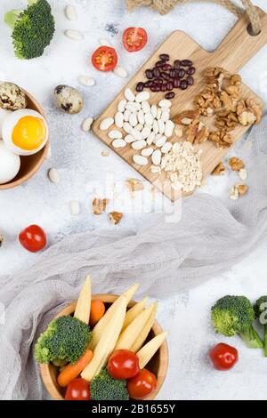 Cibo ricco di biotina. Cibo: Uova di pomodoro noci fagioli mais broccoli carota farinata d'avena su sfondo blu, cibo naturale vista dall'alto piatto lay Foto Stock