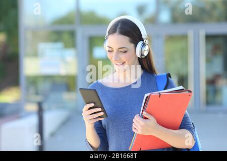 Gli studenti che utilizzano lo smartphone e ascoltano musica con cuffie nel campus universitario Foto Stock