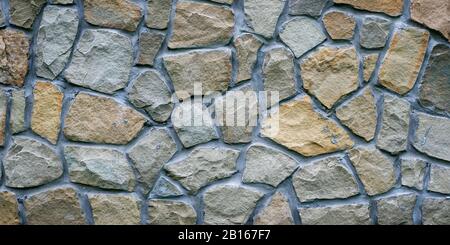 Muro di pietra grigio. Struttura di granito grigio. Superficie rocciosa irregolare del pavimento, piastrelle decorative dell'edificio della facciata. Ampio panorama. Mosaico di pietre, c Foto Stock