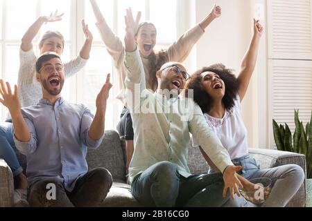 Le persone multirazziali gridano con gioia celebrando la vittoria della squadra sportiva Foto Stock