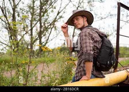 Un uomo in un cappello da cowboy si siede su un tubo del gas. Foto Stock