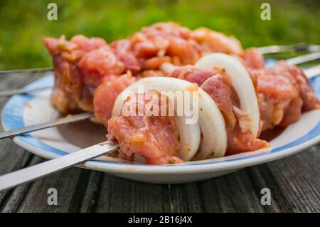 Carne di maiale cruda per il kebab shish sugli spiedini. Preparazione per un pic-nic . Messa a fuoco morbida, messa a fuoco selezionata. Foto Stock